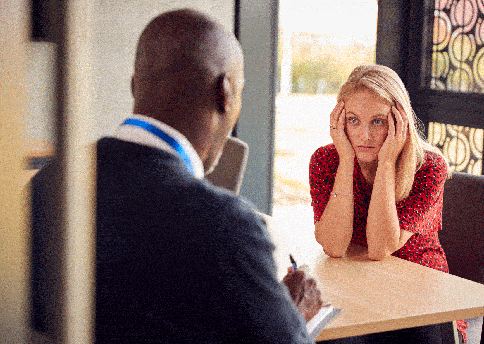 Man interviewing woman. Woman being interviewed with her head in her hands.