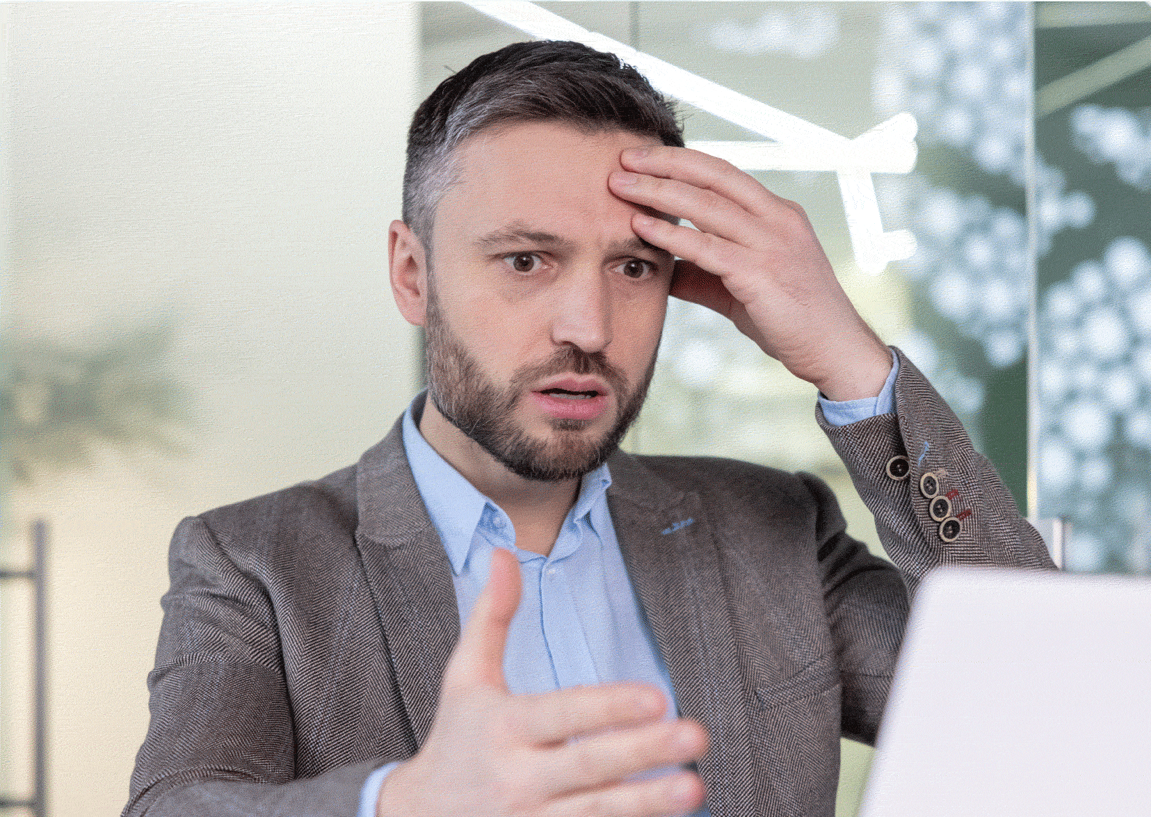 Confused man with hand to his head looking at a laptop screen