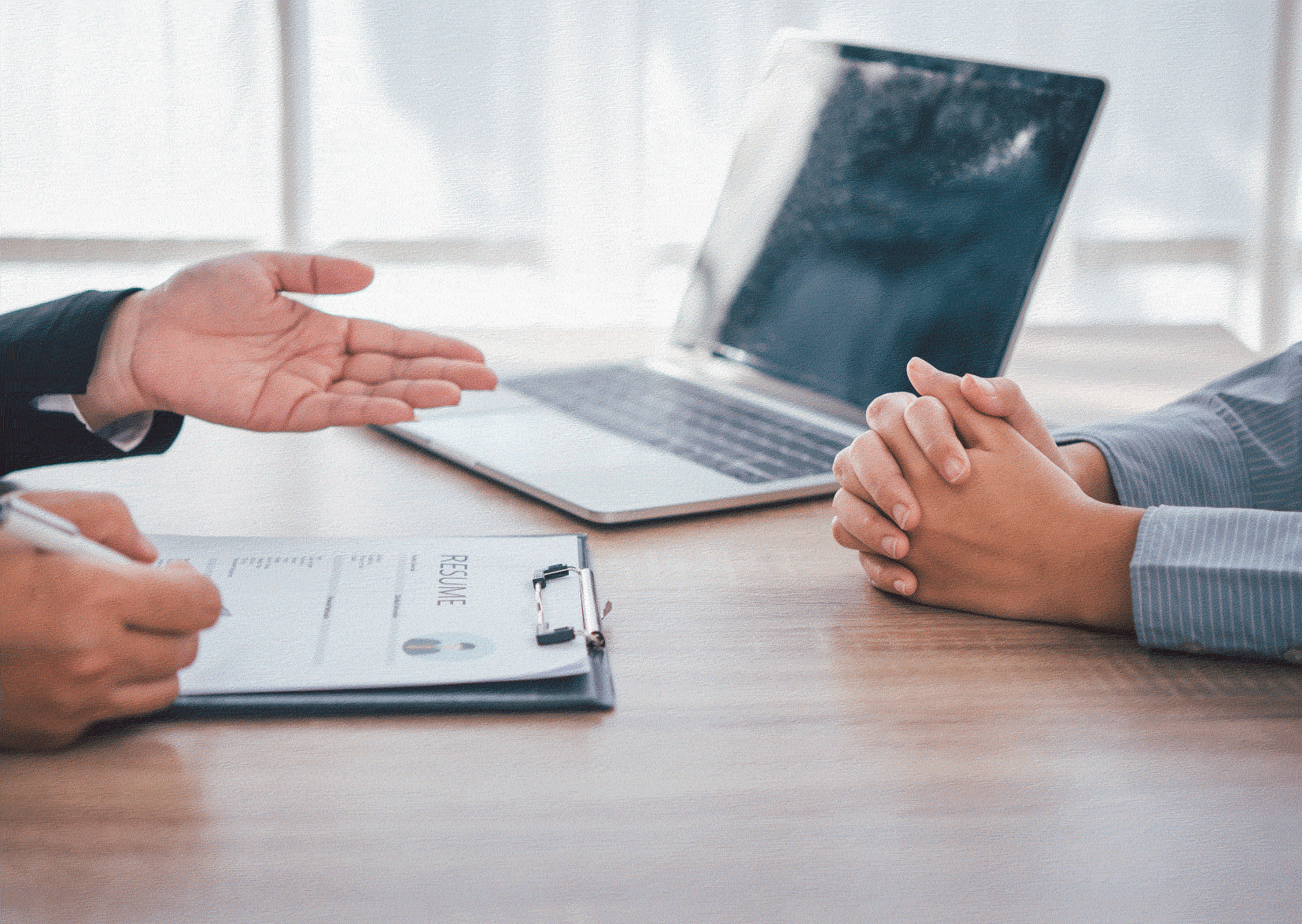 Two people talking with their hands only. Laptop in background