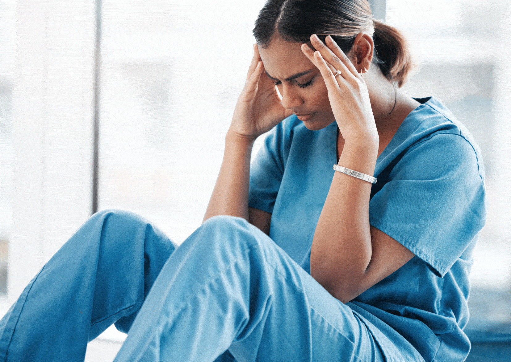 Stressed female nurse with head in her hands