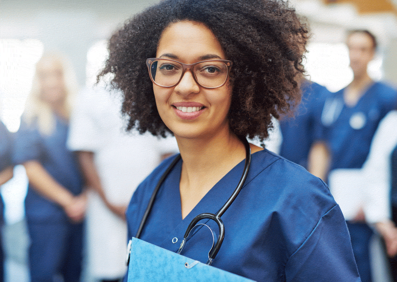 Female nurse in scrubs with paperwork in hand