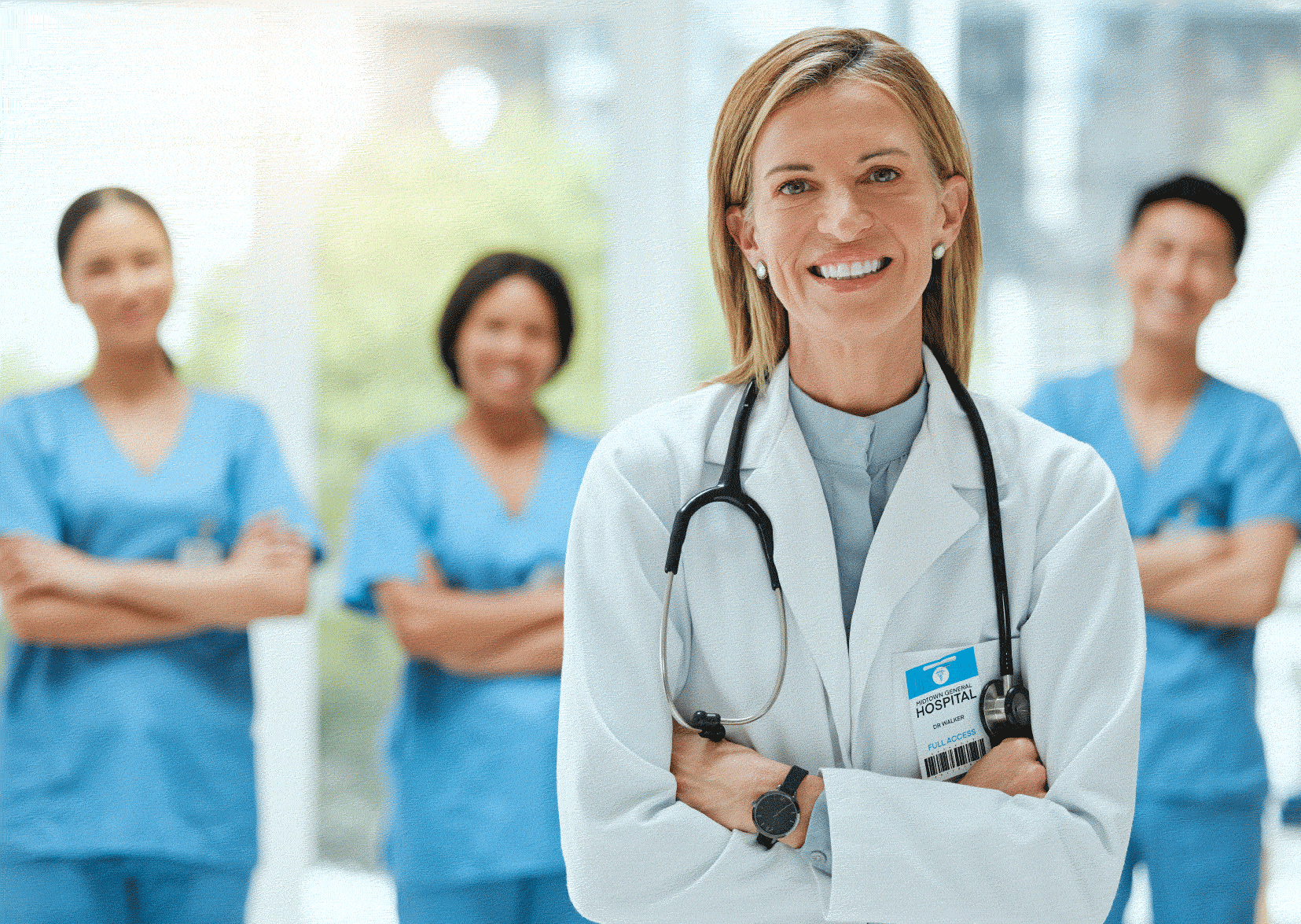 Nurse manager in white uniform with three nurses in background in blue scrubs