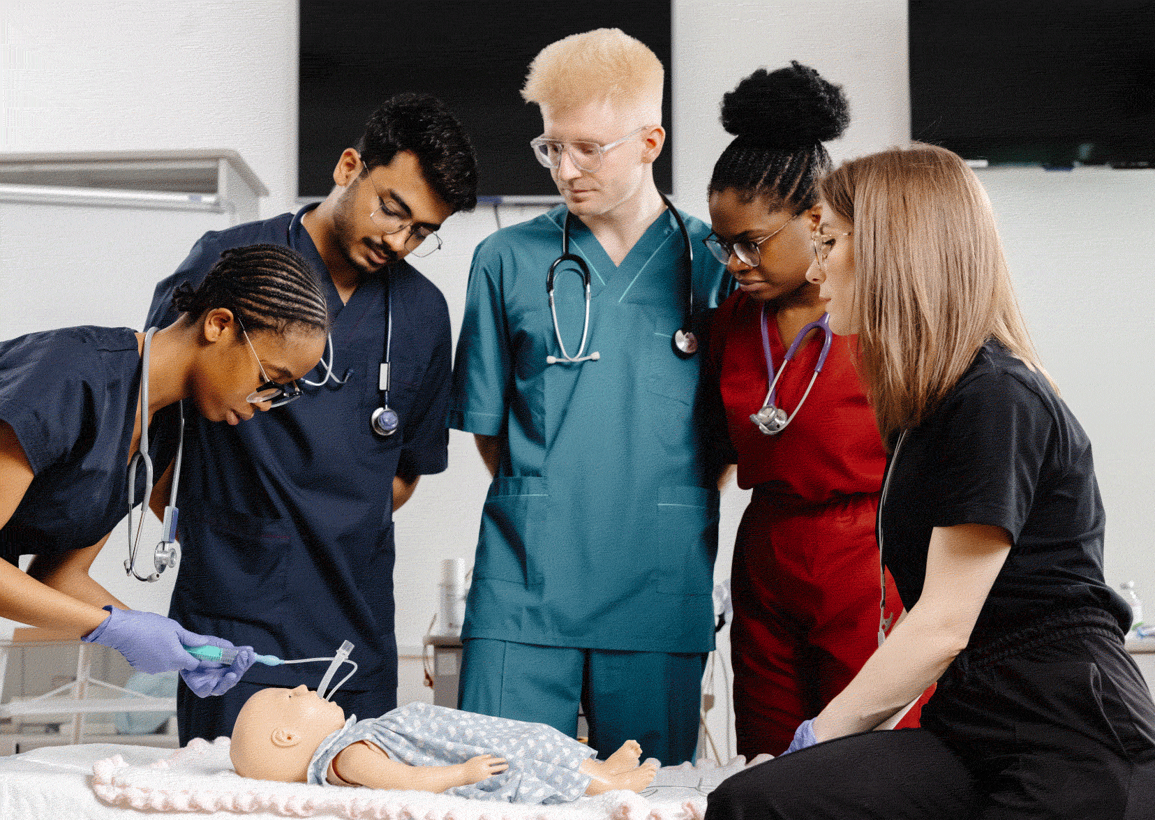 Five nurses, 2 men, 3 women training on a test dummy baby