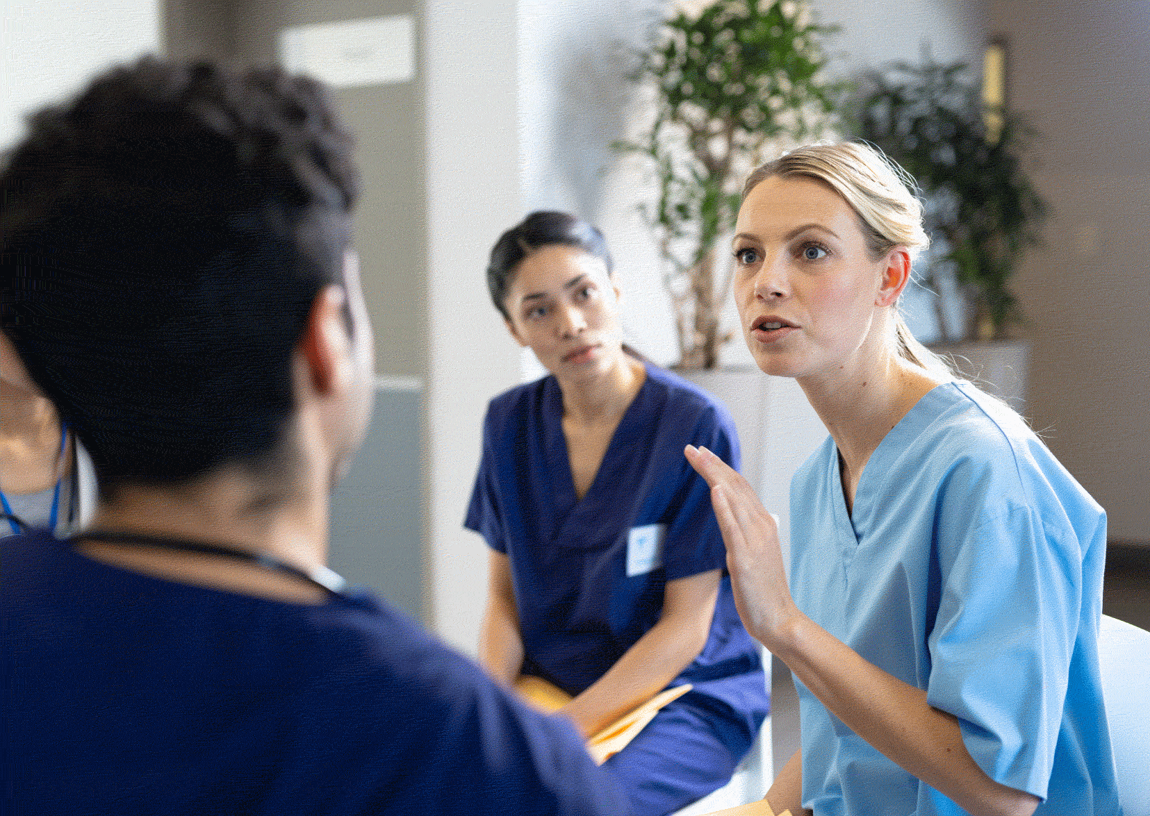 Three nurses talking in scrubs