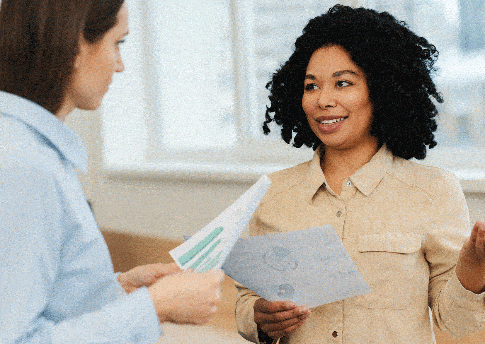 Two social workers talking. One with paperwork in hand.