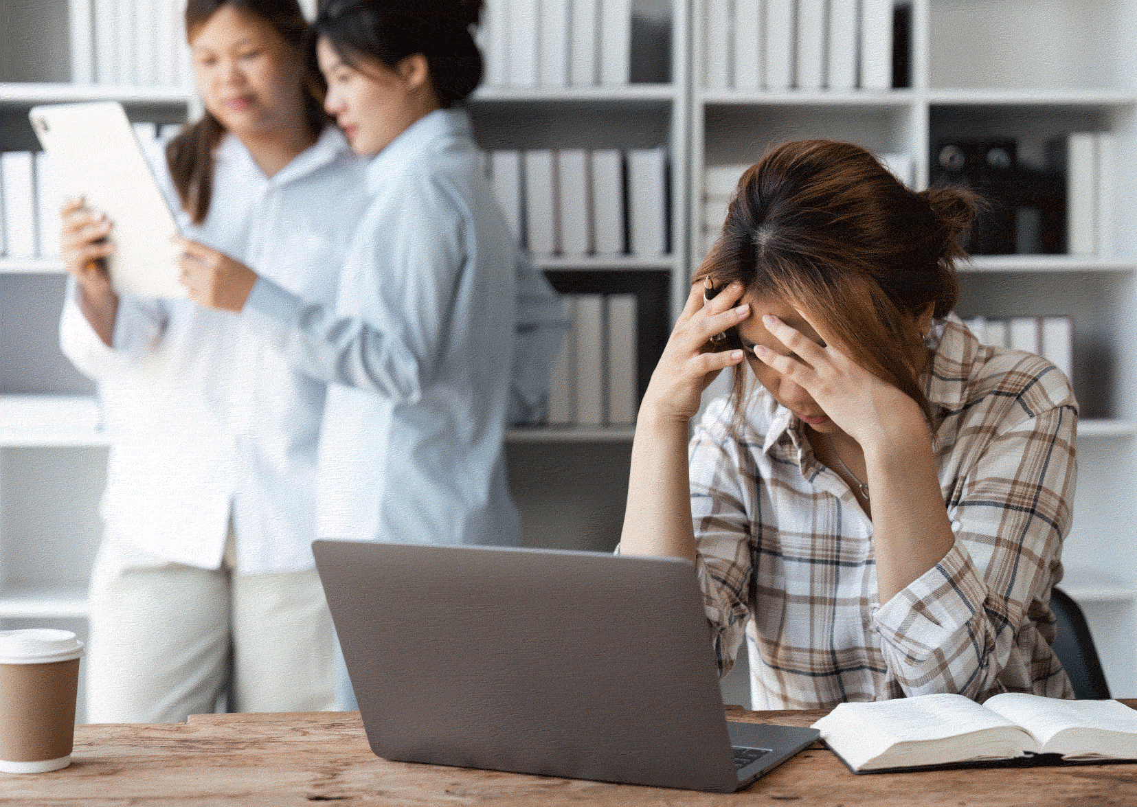 Stressed woman social worker with her head in her hands in front of a laptop