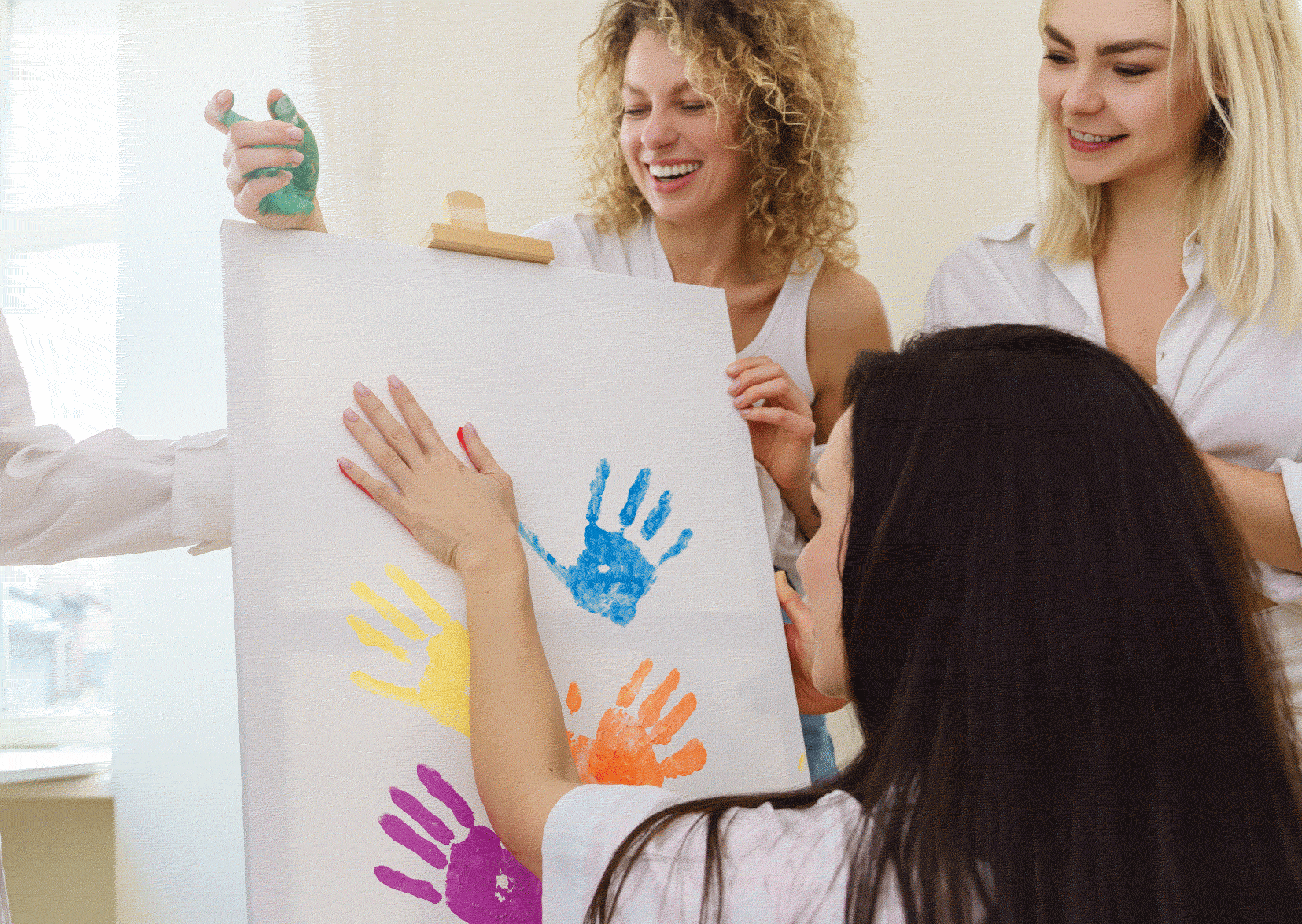 Children's Social Worker with flip chart and child is putting coloured hand prints on it