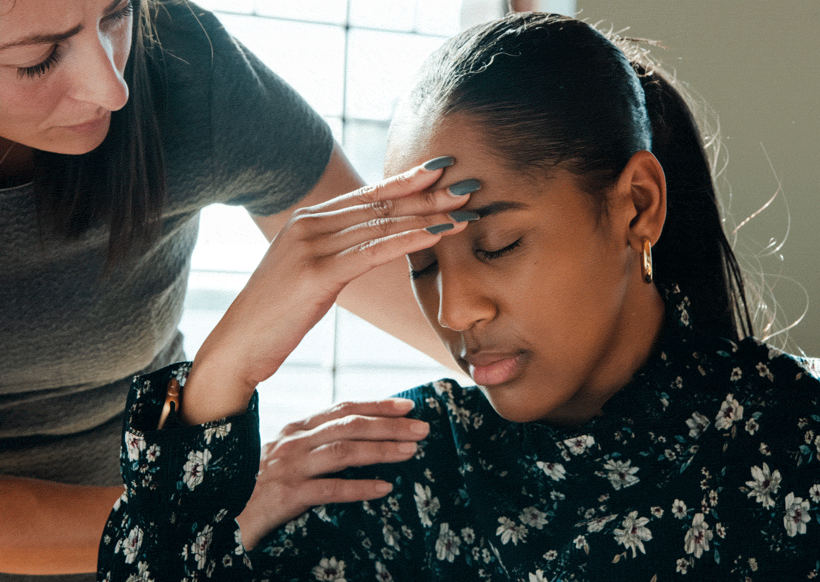 Lady with head in hands with another comforting her